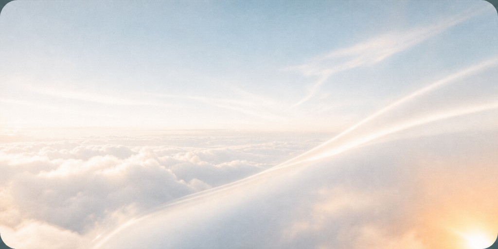 Aerial view above a layer of clouds at sunrise with warm light streaks across the sky